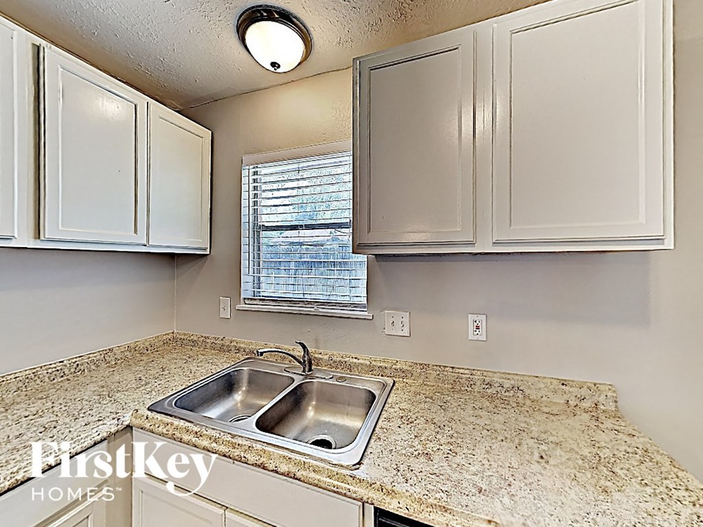 A kitchen with granite countertops and white cabinets.