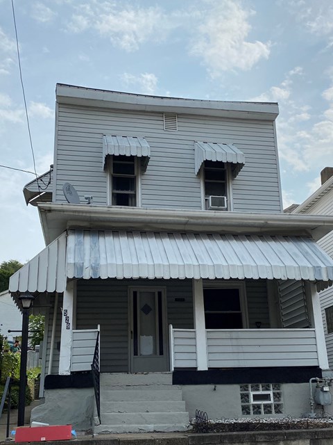 A two-story house with a grey siding and a white roof.