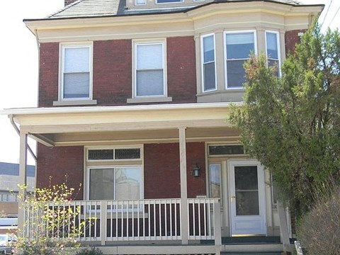 A red brick house with a white door and windows.
