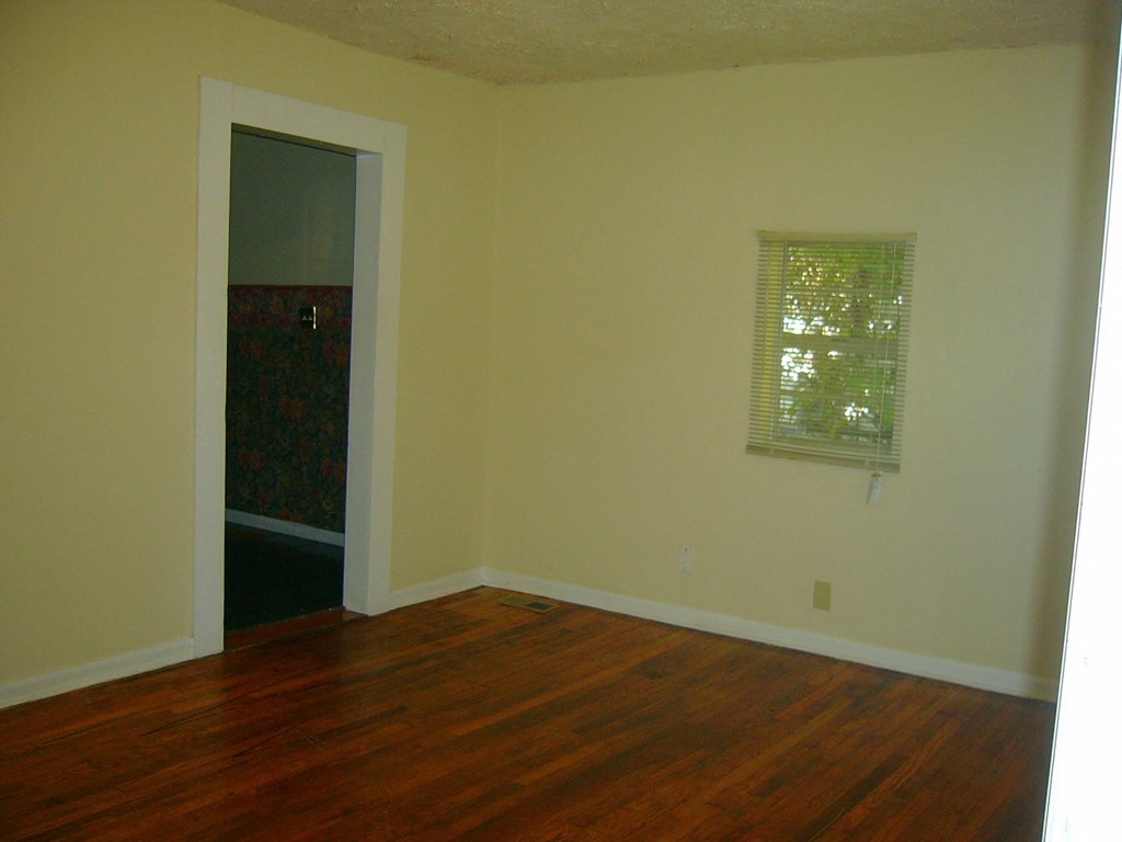 an empty living room with wooden floors and a window