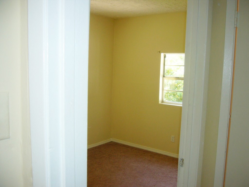 an empty room with yellow walls and a window