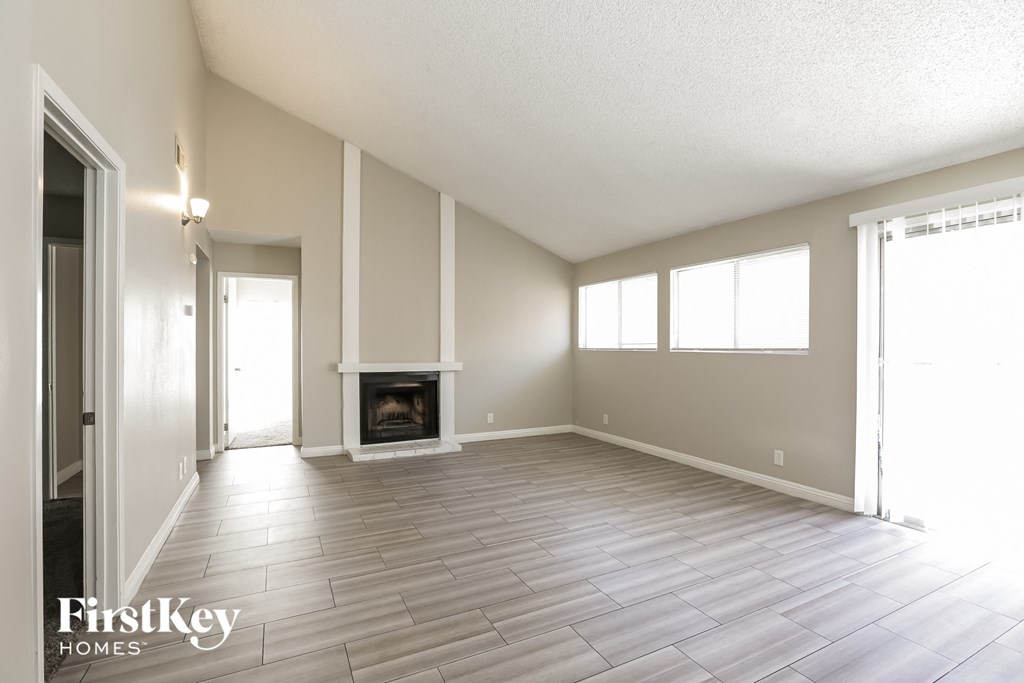 A spacious room with a fireplace and wood flooring.