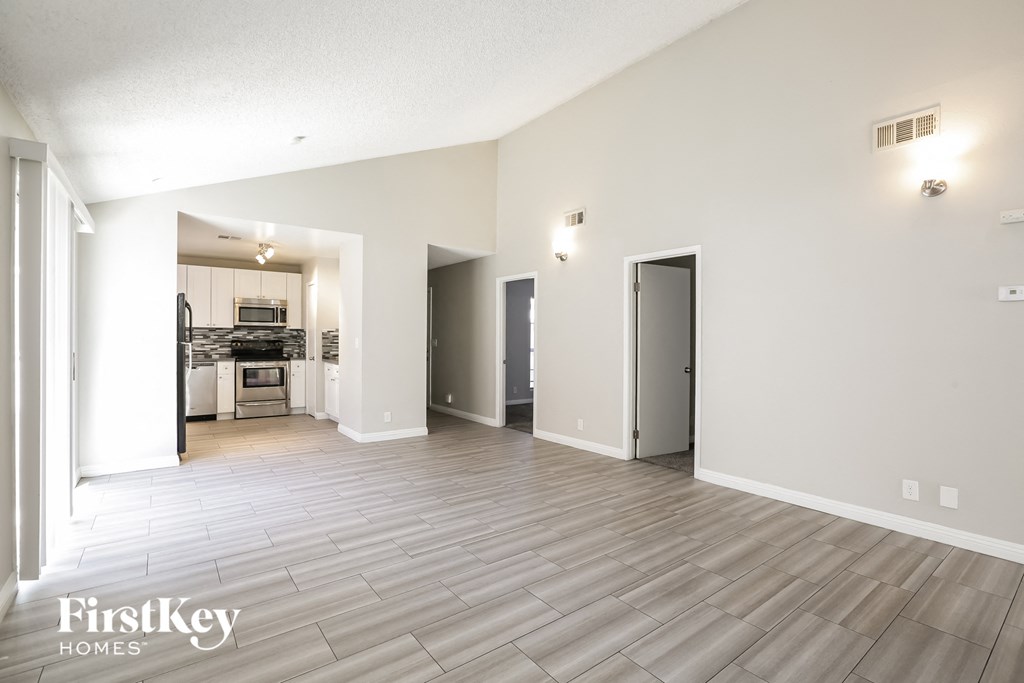 A spacious room with a kitchen in the background and a door on the right.