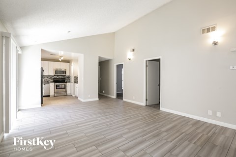 A spacious room with a kitchen in the background and a door on the right.