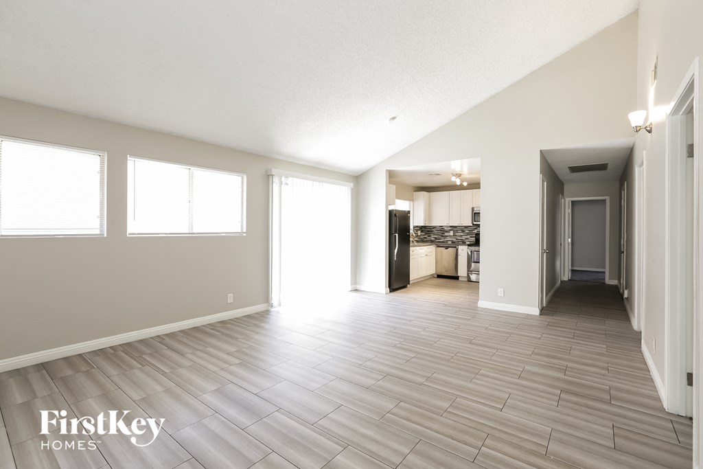 A spacious room with wooden flooring and a large window.