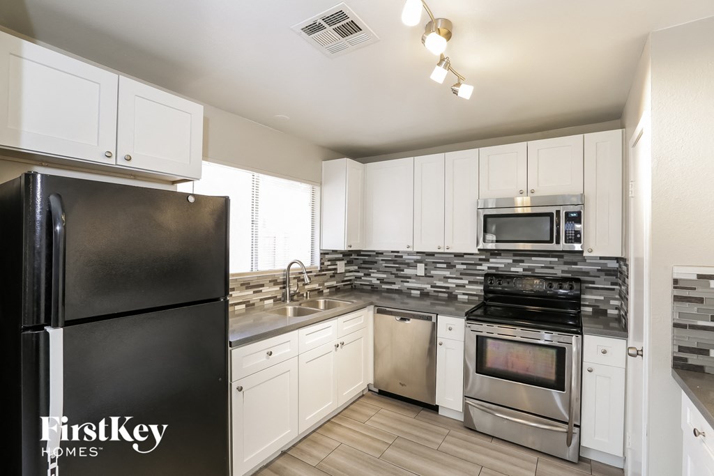 A kitchen with a black fridge and white cabinets.
