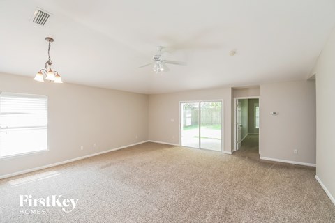a spacious living room with carpet and a ceiling fan