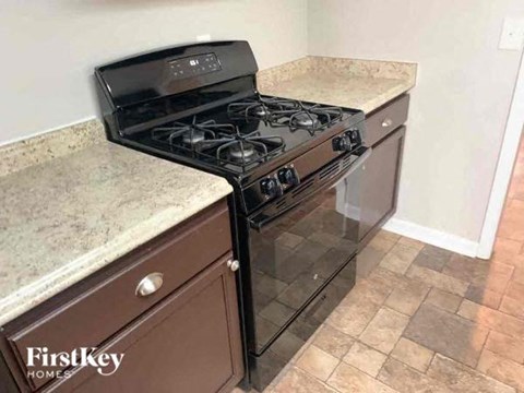 A black stove top oven with four burners and a black oven door sits on a kitchen counter.