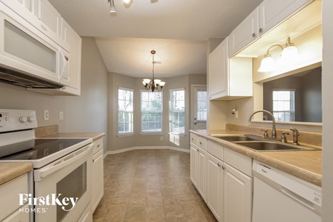 A kitchen with white cabinets and a stove top oven.