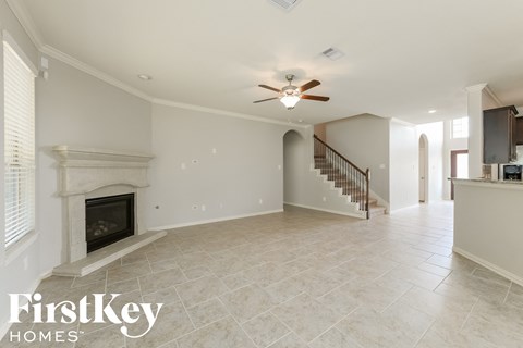 A spacious living room with a fireplace and a staircase.