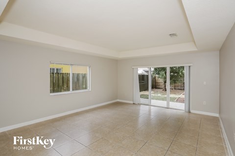 A spacious room with a tiled floor and a sliding glass door leading to a backyard.