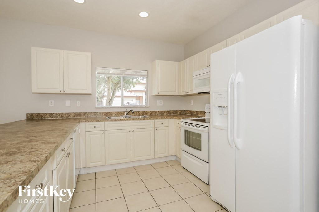 A kitchen with white appliances and cabinets.