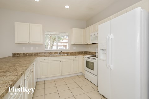A kitchen with white appliances and cabinets.