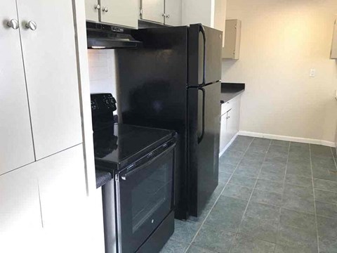 a black refrigerator in a kitchen with white cabinets