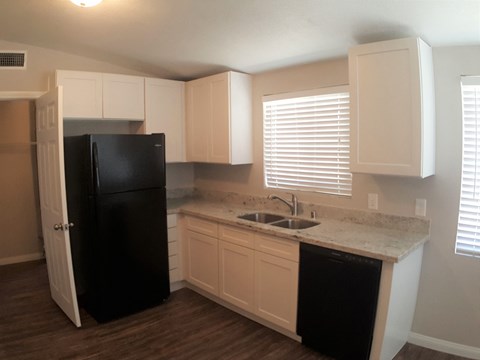 A kitchen with a black refrigerator and white cabinets.