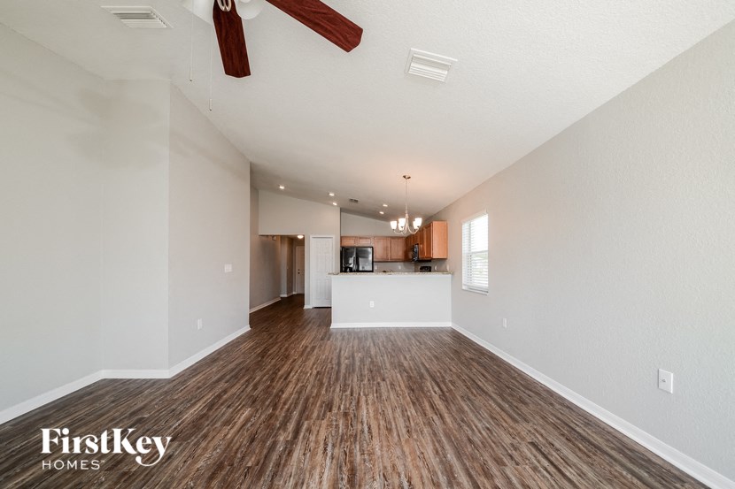 A spacious room with wooden flooring and a ceiling fan.