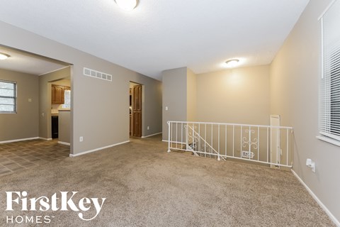 A spacious living room with a staircase and a window.