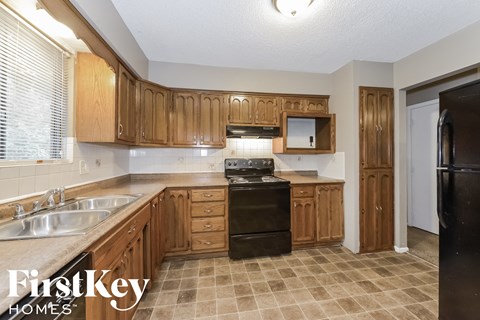 A kitchen with wooden cabinets and a black refrigerator.