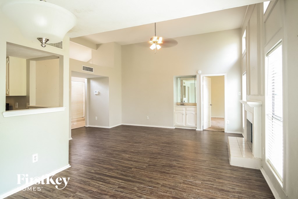 an empty living room with a wood floor and a ceiling fan