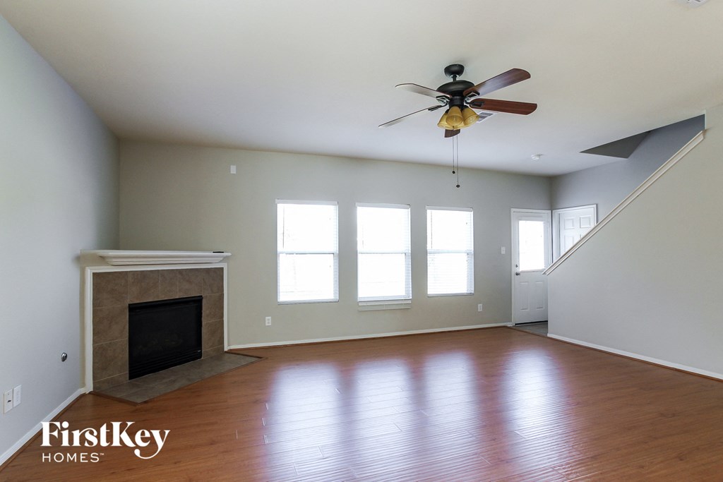 an empty living room with a ceiling fan and a fireplace