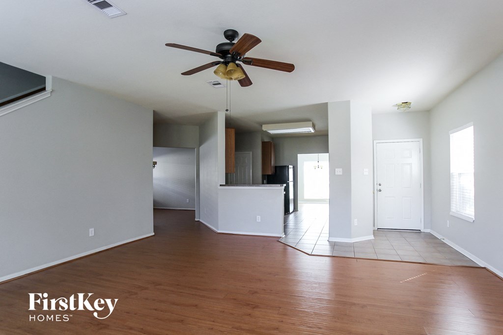 an empty living room and kitchen with a ceiling fan