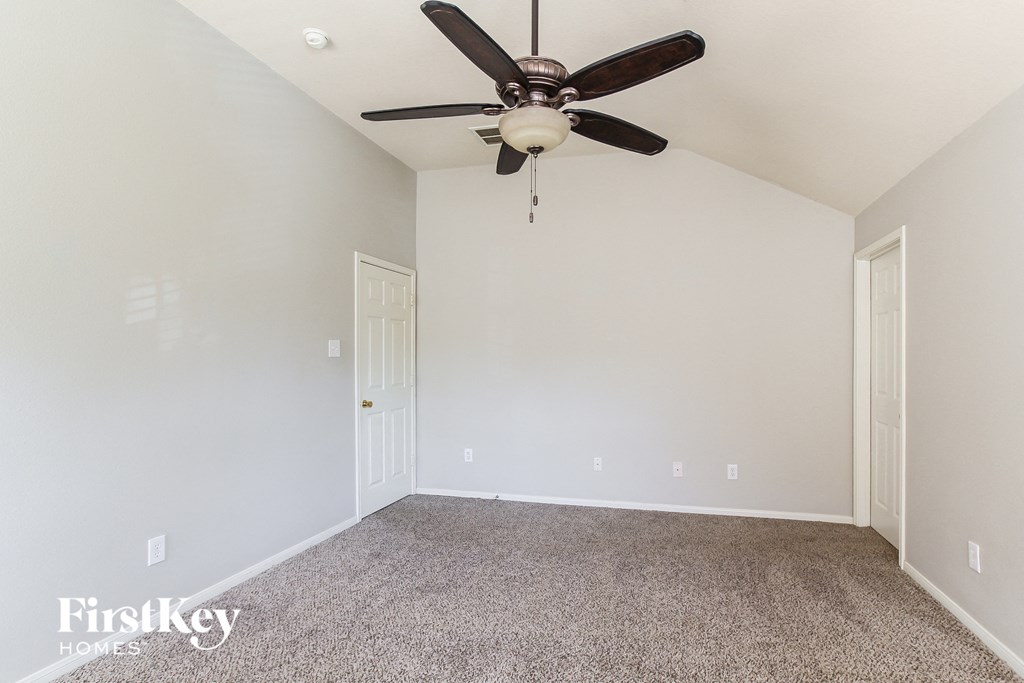 a empty room with a ceiling fan and carpet