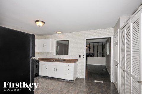 A kitchen with white cabinets and a black refrigerator.