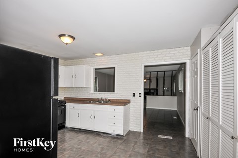 A kitchen with white cabinets and a black refrigerator.
