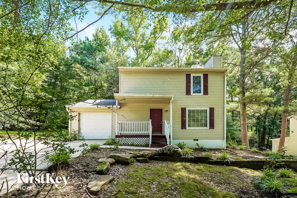 a small yellow house in the woods with trees