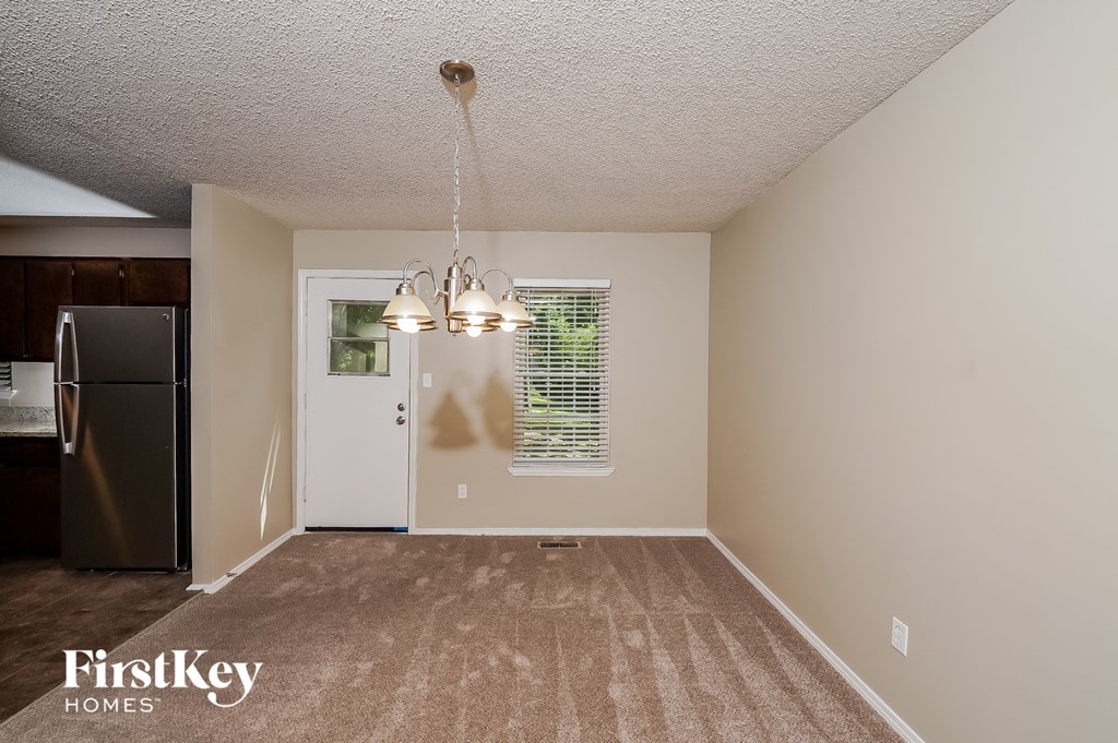 an empty living room with a refrigerator and a window