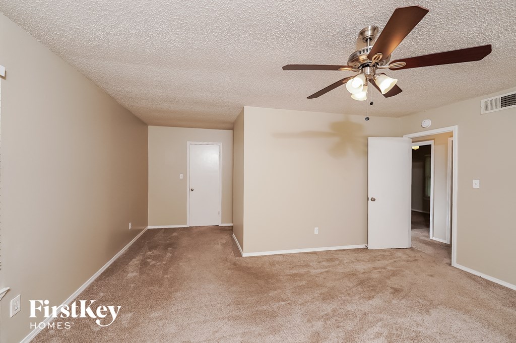 an empty living room with a ceiling fan and a closet