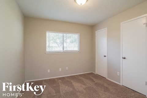 a bedroom with carpet and a window and a door
