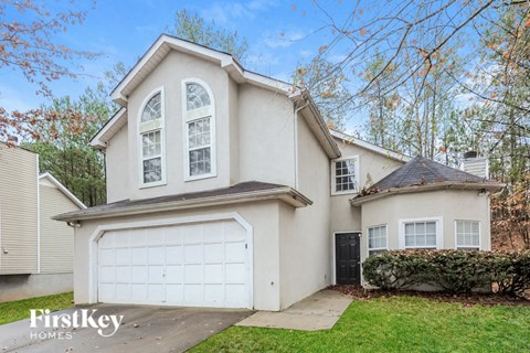 A house with a garage and a tree in front of it.