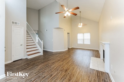 A spacious room with a staircase and a fireplace.