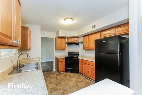 A kitchen with wooden cabinets and a black refrigerator.