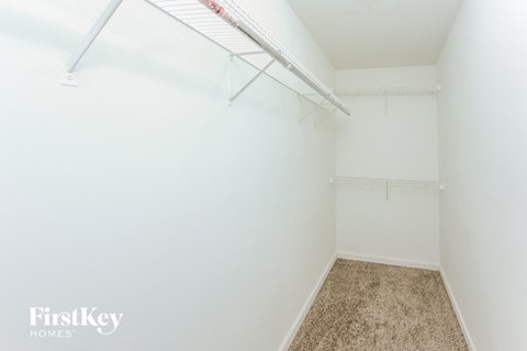 A white bedroom with a carpeted floor and a white bed frame.