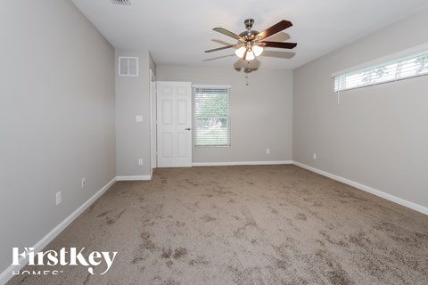 A room with a ceiling fan and a door leading to another room.
