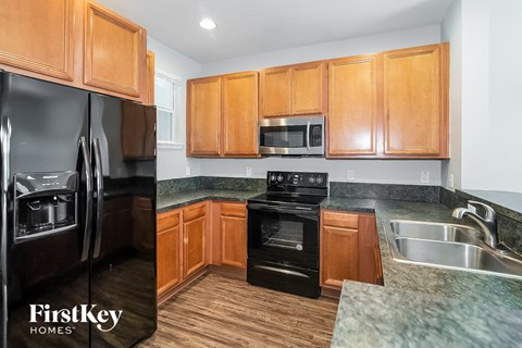 A kitchen with wooden cabinets and a black refrigerator.