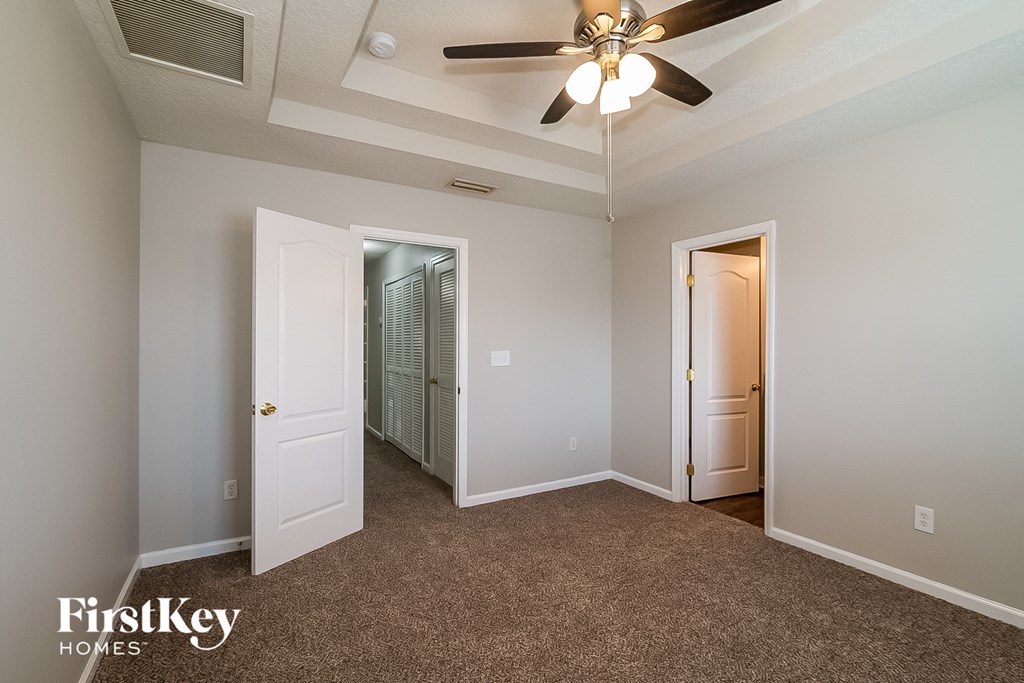 A room with a carpeted floor and a ceiling fan.