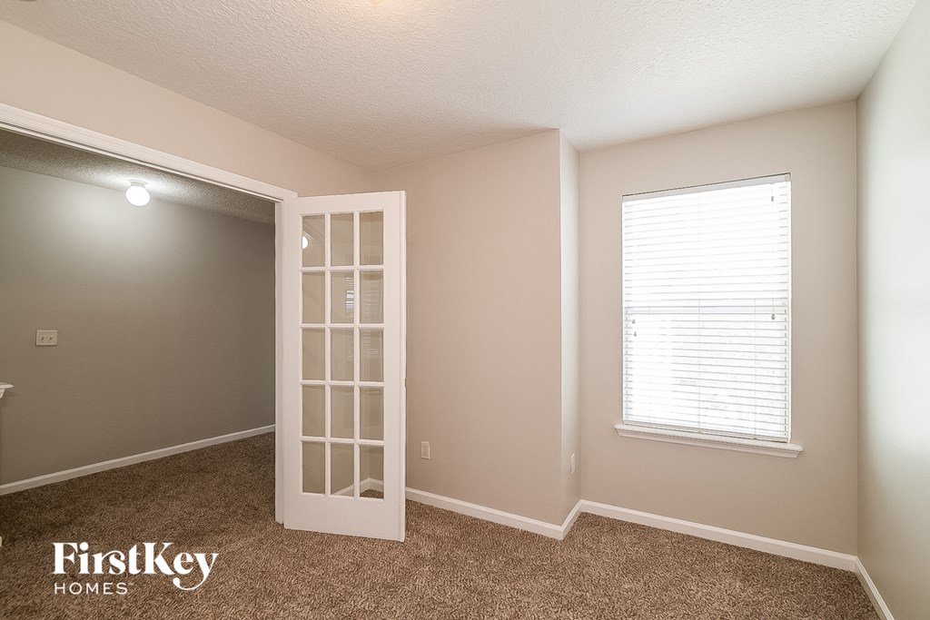 A room with a carpeted floor and a window with blinds.