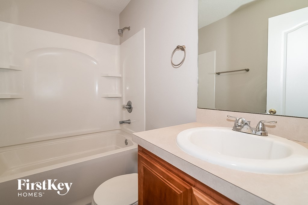 A white bathroom with a wooden cabinet and a white toilet.