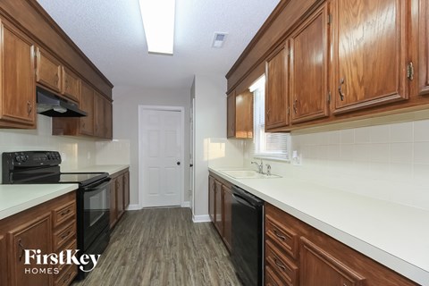 a kitchen with wooden cabinets and white counter tops and black appliances