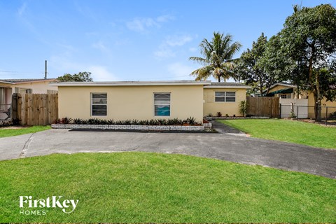 a home with a driveway and a lawn and a palm tree
