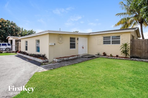 a beige house with a lawn and palm tree