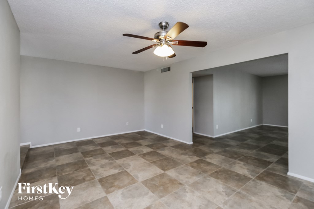 A room with a ceiling fan and tile flooring.
