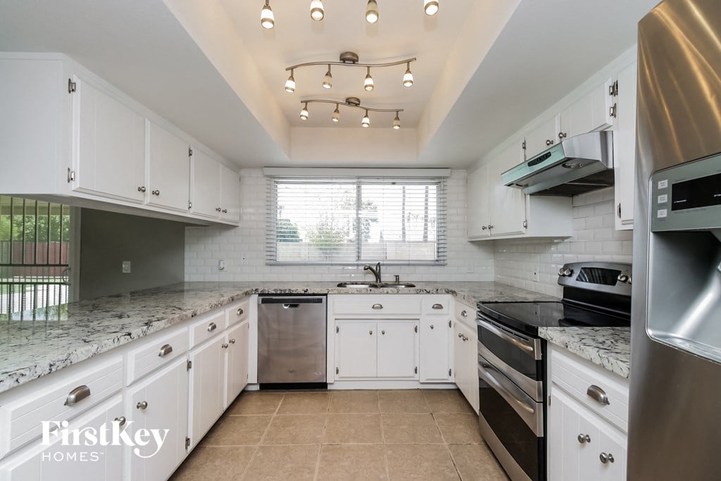 A kitchen with white cabinets and a marble countertop.