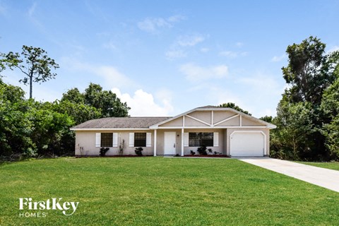 A house with a white garage door is surrounded by trees.