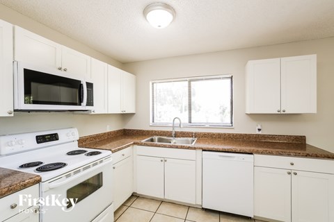 A kitchen with white cabinets and a brown countertop.