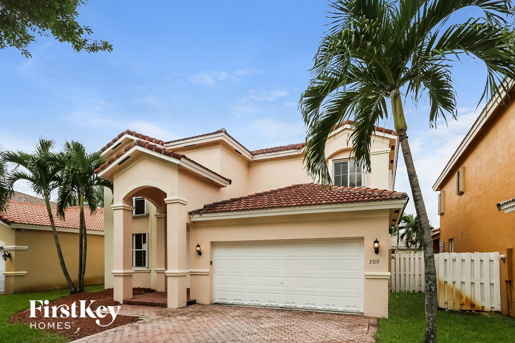 A house with a white garage door and a palm tree in front.