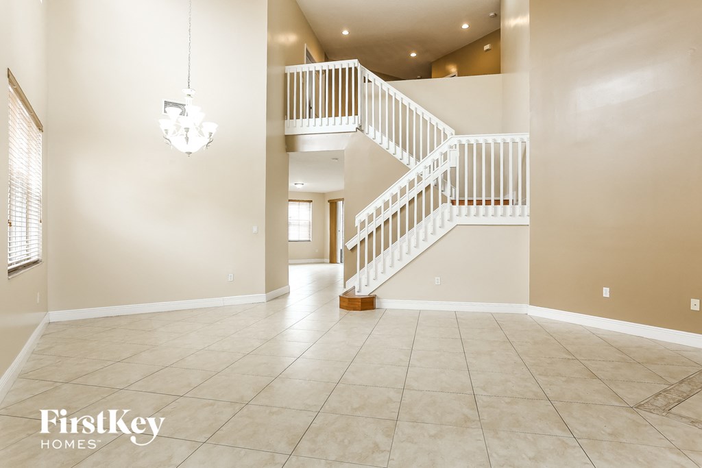 A spacious foyer with a staircase and a chandelier.